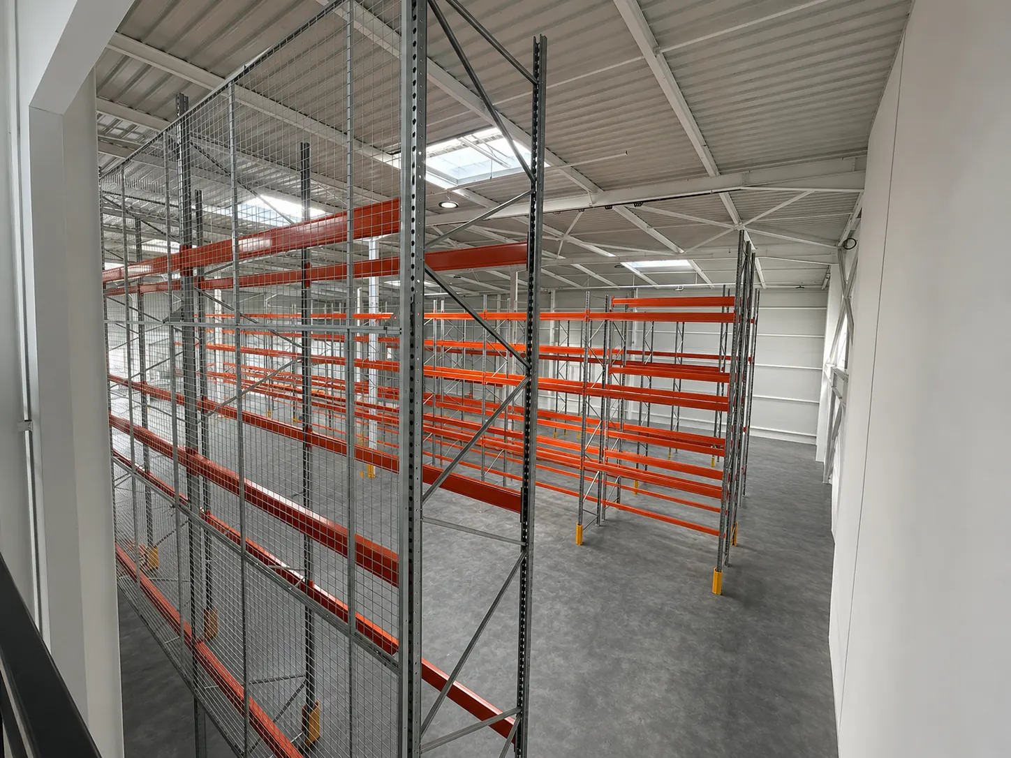 Zone de racks à palettes protégée par un box grillagé dans le centre logistique